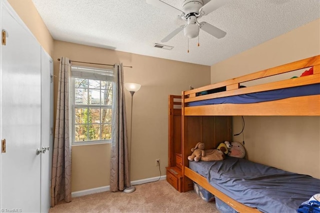 bedroom featuring light colored carpet, visible vents, a textured ceiling, and baseboards