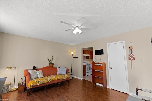 living area featuring a textured ceiling, baseboards, dark wood finished floors, and a ceiling fan