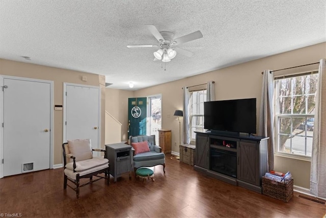 interior space with baseboards, visible vents, ceiling fan, dark wood-style flooring, and a textured ceiling