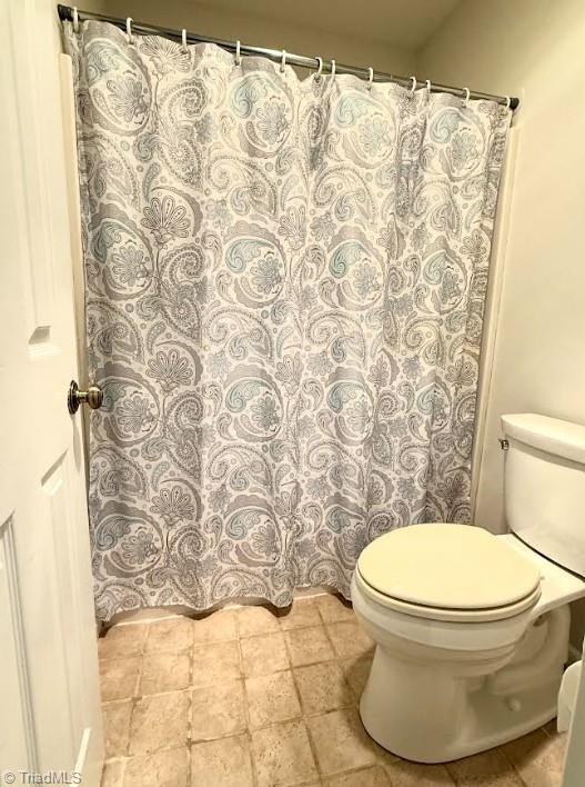 bathroom featuring curtained shower and toilet