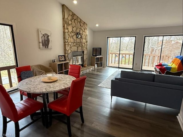 dining area featuring recessed lighting, lofted ceiling, wood finished floors, and a fireplace