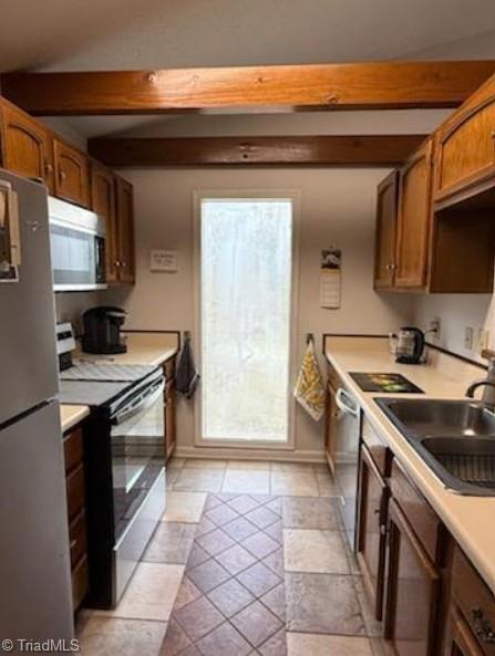 kitchen with beam ceiling, stainless steel appliances, light countertops, and a sink