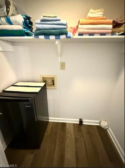 laundry area featuring laundry area, dark wood-type flooring, baseboards, and washer hookup