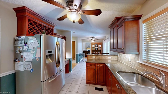 kitchen featuring light tile patterned floors, ceiling fan, a sink, stainless steel refrigerator with ice dispenser, and a peninsula