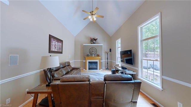 living area with a healthy amount of sunlight, light wood finished floors, ceiling fan, and a glass covered fireplace