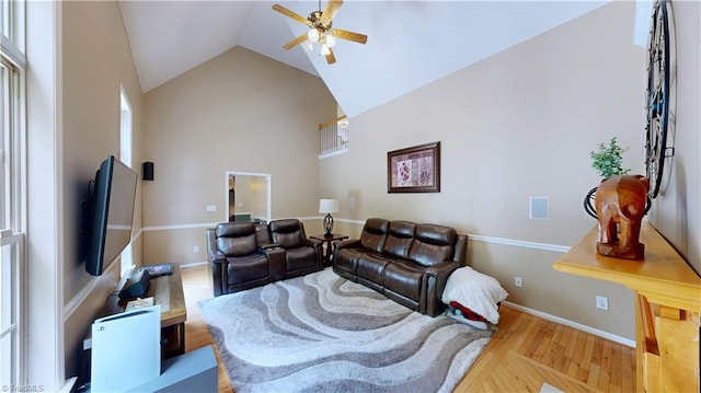 living area with ceiling fan, wood finished floors, high vaulted ceiling, and baseboards