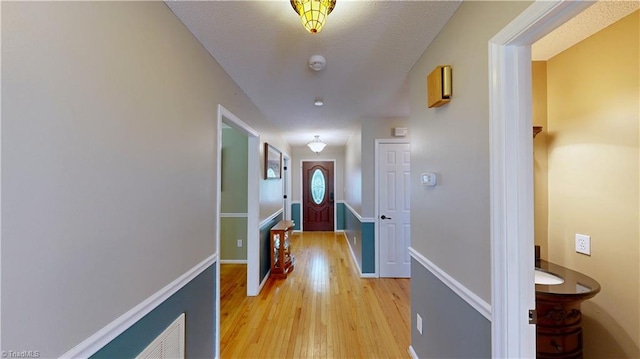 corridor featuring light wood finished floors and baseboards