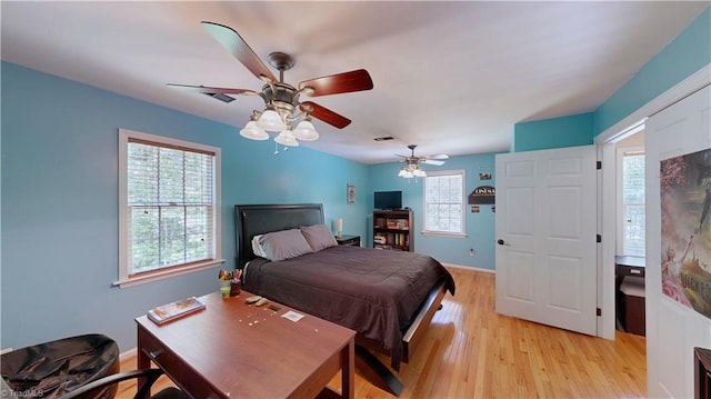 bedroom with baseboards, a ceiling fan, multiple windows, and light wood-style flooring