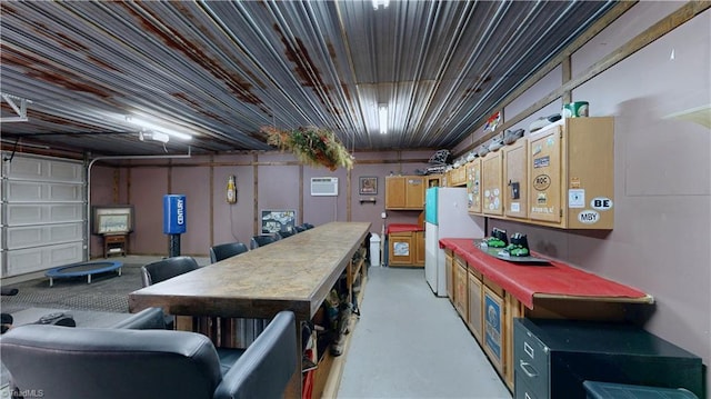 basement with freestanding refrigerator, an AC wall unit, and a garage