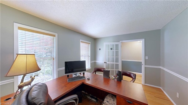 office area with a textured ceiling, light wood-style flooring, and baseboards