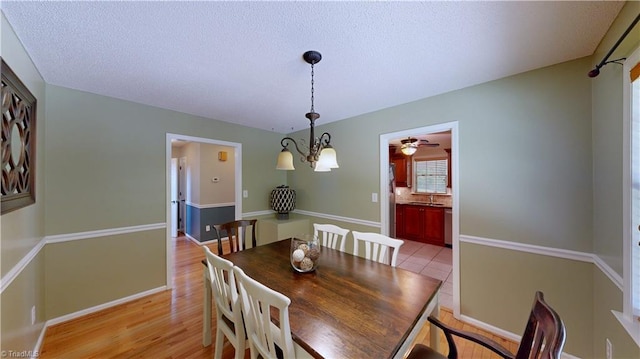 dining area with baseboards, a ceiling fan, and light wood finished floors