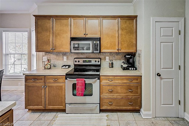 kitchen with backsplash, light tile patterned floors, ornamental molding, and appliances with stainless steel finishes