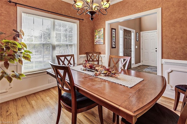 dining space featuring ornamental molding, a wealth of natural light, wood-type flooring, and a chandelier