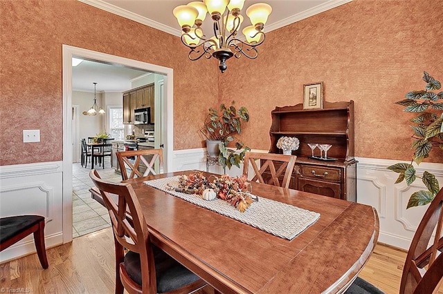 dining space with an inviting chandelier, light hardwood / wood-style flooring, and ornamental molding