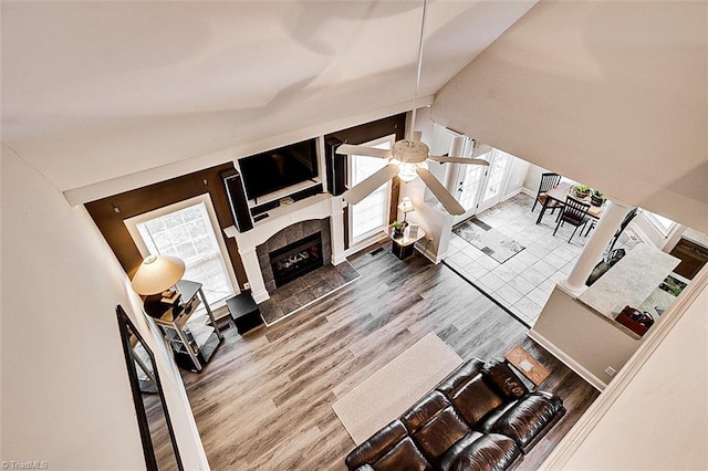 living room featuring hardwood / wood-style flooring, high vaulted ceiling, ceiling fan, and a tiled fireplace