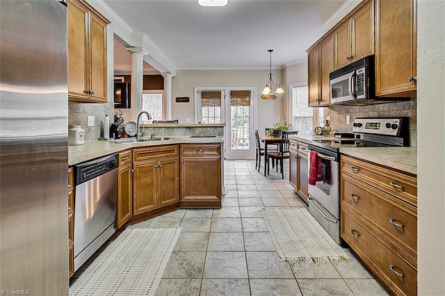 kitchen featuring ornamental molding, sink, ornate columns, appliances with stainless steel finishes, and an inviting chandelier