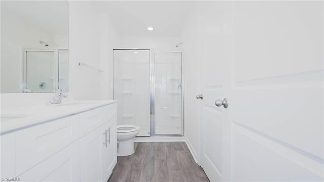 bathroom with wood-type flooring, vanity, an enclosed shower, and toilet