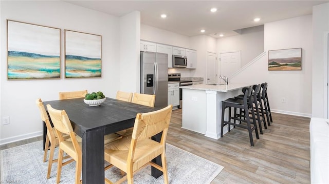 dining area featuring sink and light wood-type flooring
