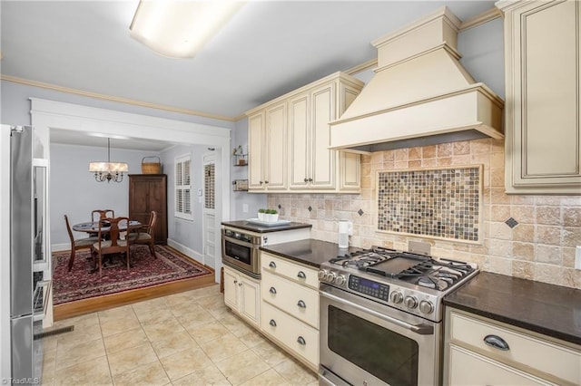 kitchen featuring custom exhaust hood, appliances with stainless steel finishes, cream cabinets, hanging light fixtures, and light wood-type flooring