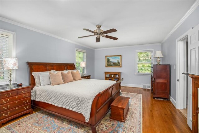 bedroom with ornamental molding, hardwood / wood-style flooring, and multiple windows