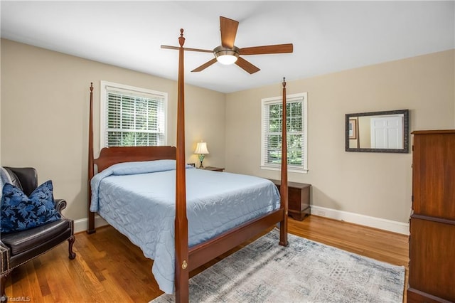 bedroom with ceiling fan, multiple windows, and hardwood / wood-style floors