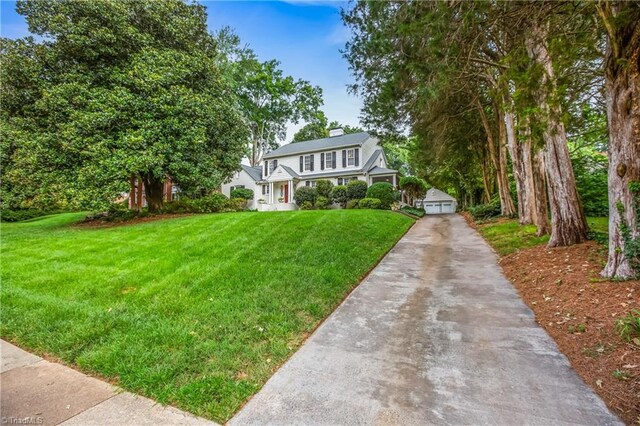 view of front of property featuring a garage, a front lawn, and an outbuilding