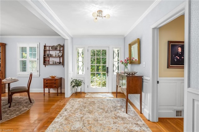 doorway with light wood-type flooring and crown molding