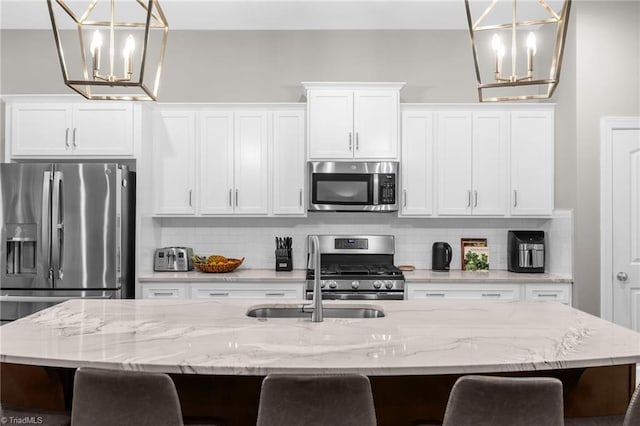 kitchen featuring decorative backsplash, a chandelier, stainless steel appliances, and a sink