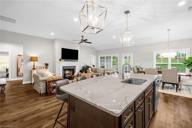 kitchen featuring a sink, dark wood-style flooring, visible vents, decorative light fixtures, and a fireplace