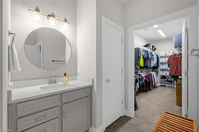 bathroom with a walk in closet, wood finished floors, and vanity