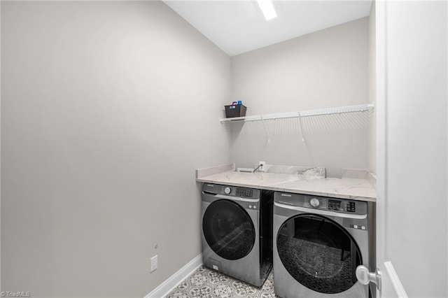 clothes washing area featuring washer and dryer, baseboards, and laundry area