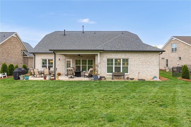 back of house with a lawn, brick siding, a patio, and a shingled roof