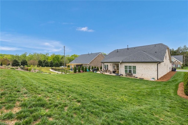 back of house with a patio area, a lawn, and brick siding