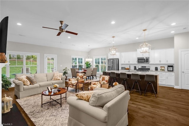 living room featuring recessed lighting, dark wood finished floors, and ceiling fan with notable chandelier