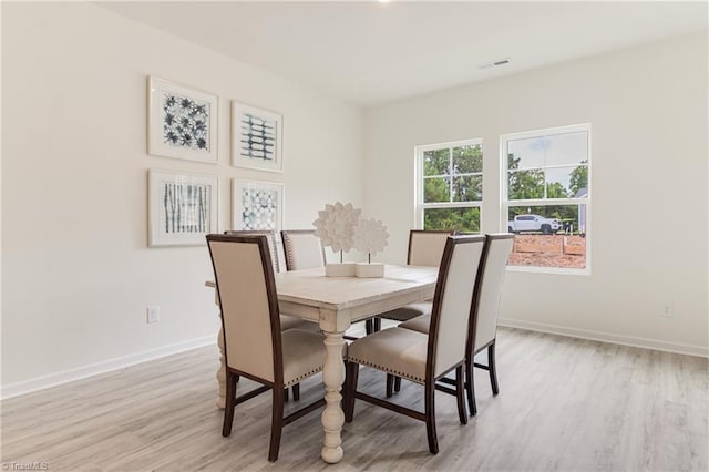 dining room featuring light wood finished floors, visible vents, and baseboards