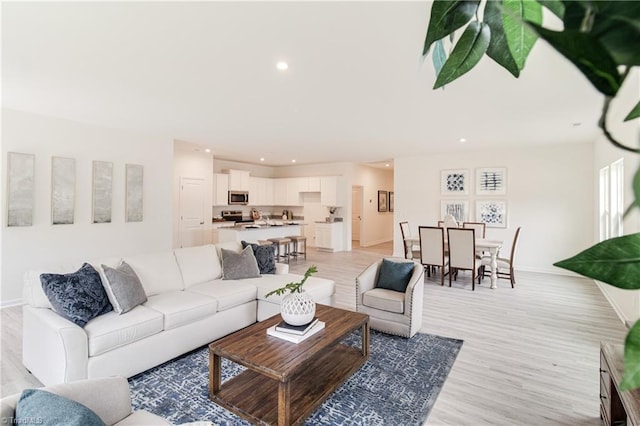 living room featuring recessed lighting, baseboards, and light wood-style floors