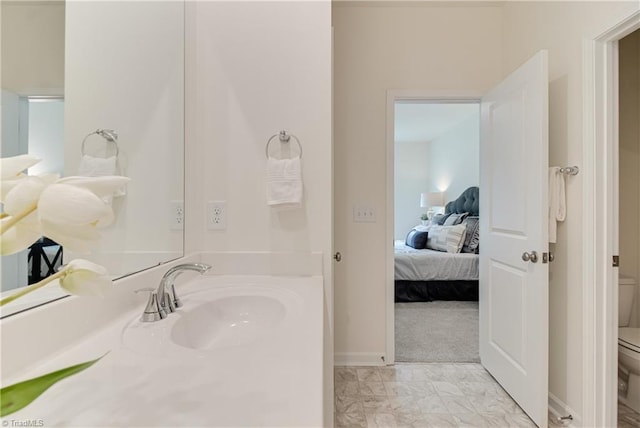 bathroom featuring baseboards, vanity, toilet, and ensuite bathroom