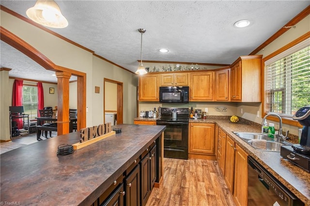 kitchen featuring decorative columns, crown molding, sink, black appliances, and decorative light fixtures