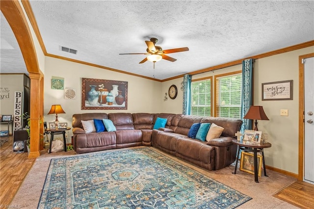 living room featuring a textured ceiling, carpet floors, ceiling fan, and ornamental molding