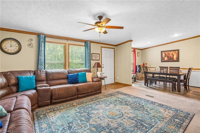 living room featuring carpet flooring, ceiling fan, crown molding, and a textured ceiling