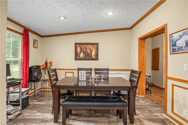 dining space featuring lofted ceiling, a textured ceiling, hardwood / wood-style flooring, and ornamental molding