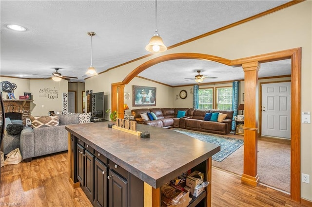 kitchen featuring a center island, dark brown cabinetry, ornamental molding, and ceiling fan