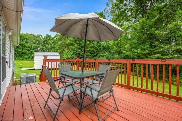 wooden terrace with a lawn, a storage unit, and cooling unit