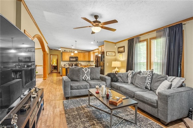 living room with ornamental molding, a textured ceiling, ceiling fan, light hardwood / wood-style floors, and lofted ceiling