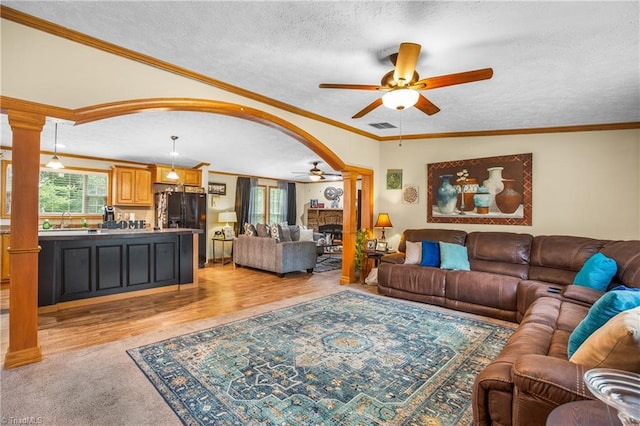 living room featuring sink, crown molding, ceiling fan, a textured ceiling, and light colored carpet