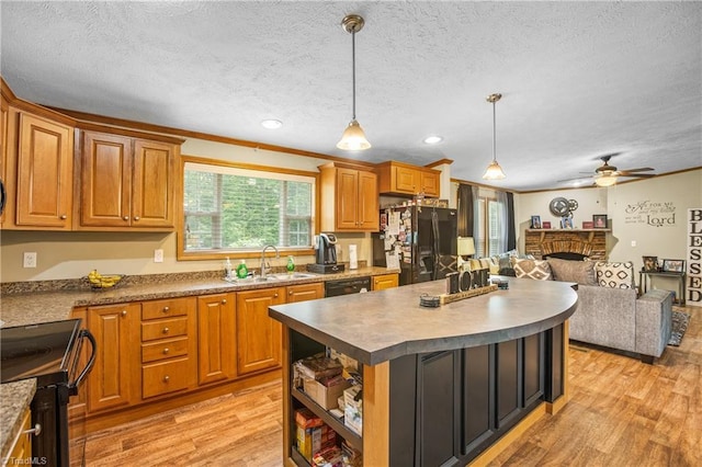 kitchen with ornamental molding, sink, black appliances, pendant lighting, and a center island