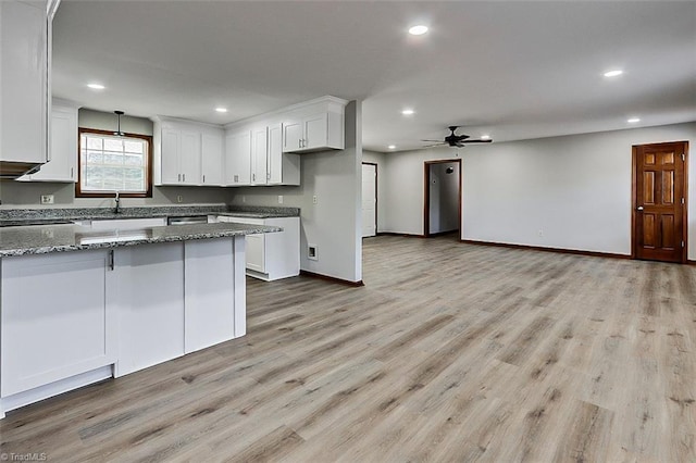 kitchen featuring light wood finished floors, dark stone counters, and white cabinets