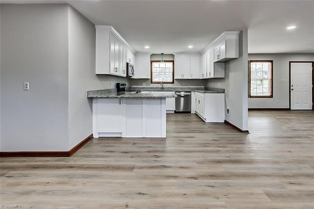 kitchen with stainless steel appliances, stone countertops, white cabinetry, a peninsula, and baseboards