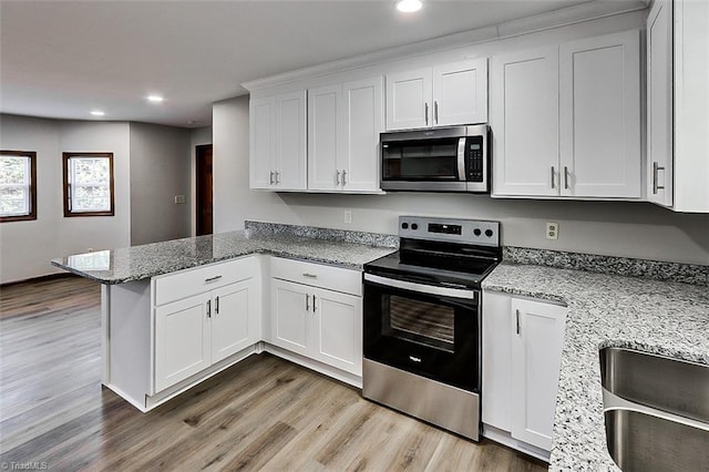 kitchen featuring white cabinets, light stone countertops, a peninsula, and stainless steel appliances