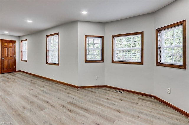 spare room featuring baseboards, visible vents, and light wood-style floors